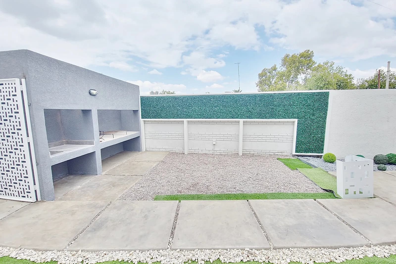 Patio del Eco Home con parrillero, mesada exterior y jardín de bajo mantenimiento